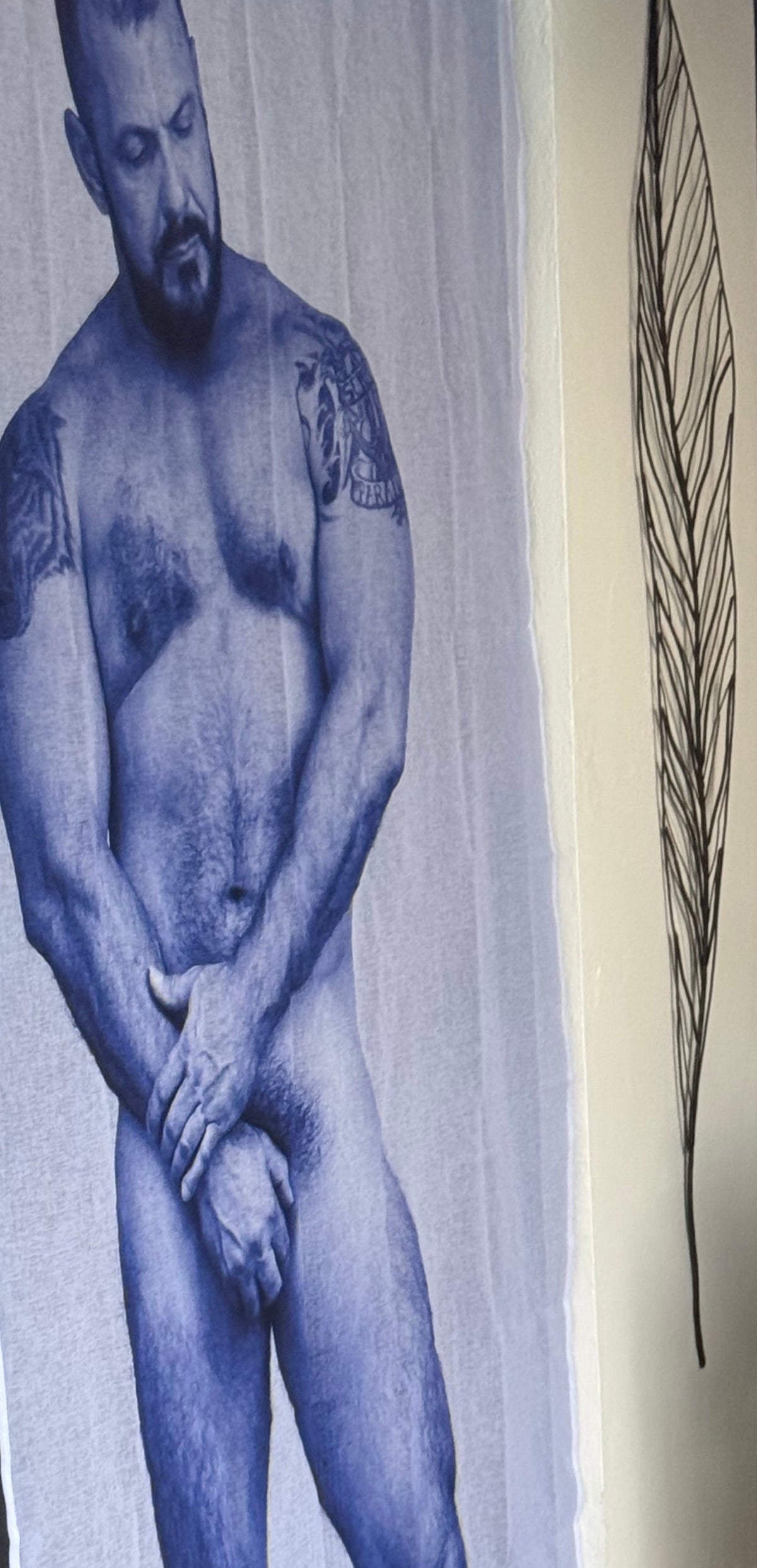 A large white fabric banner or curtain featuring a blue-toned illustration of a muscular, tattooed man, hanging next to a glass door in an indoor-outdoor doorway setting.